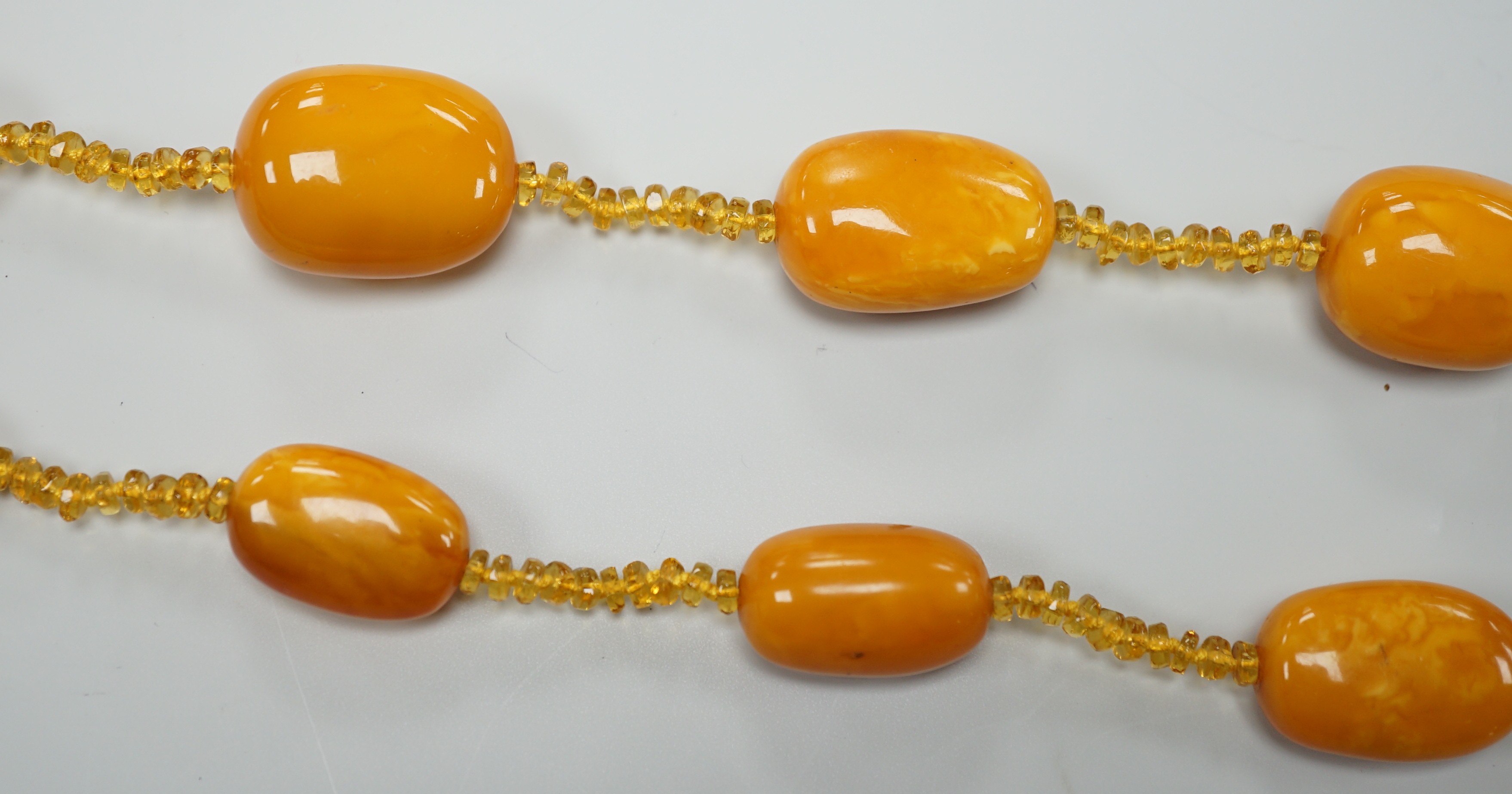A single strand graduated fifteen amber bead necklace, with multiple amber? spacers, 84cm, gross weight 89 grams.